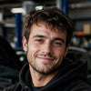 Man standing in a garage with cars in the background
