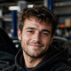 Man standing in a garage with cars in the background